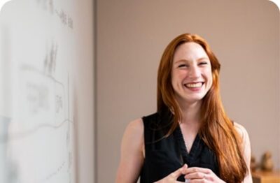 Smiling healthcare professional standing beside a whiteboard in an office